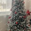 Ein schneebedeckter künstlicher Weihnachtsbaum, geschmückt mit rotem Weihnachtsschmuck, im Wohnzimmer,