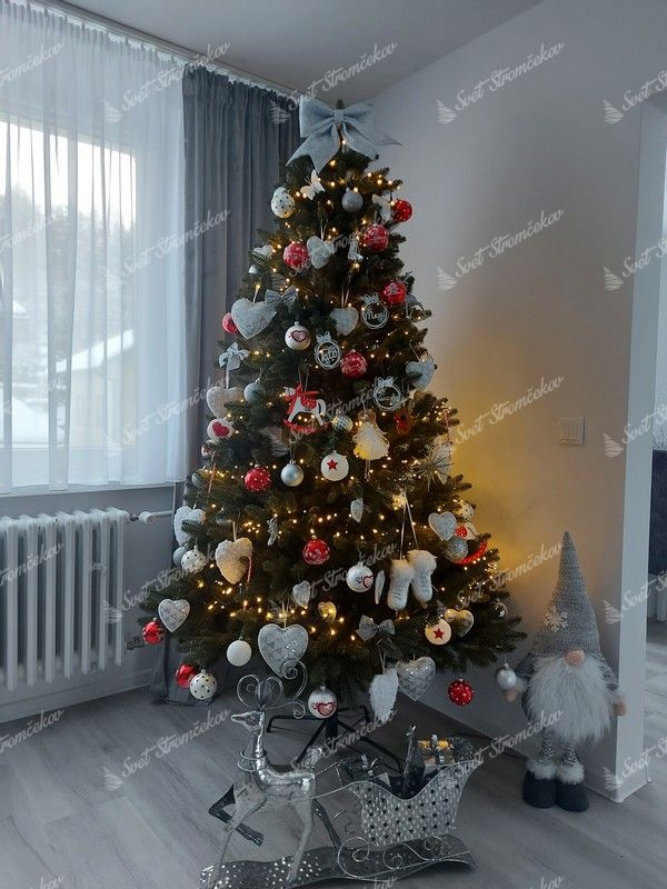 Umelý vianočný stromček s tmavozelenými vetvičkami, ozdobený červeno-bielymi ozdobami