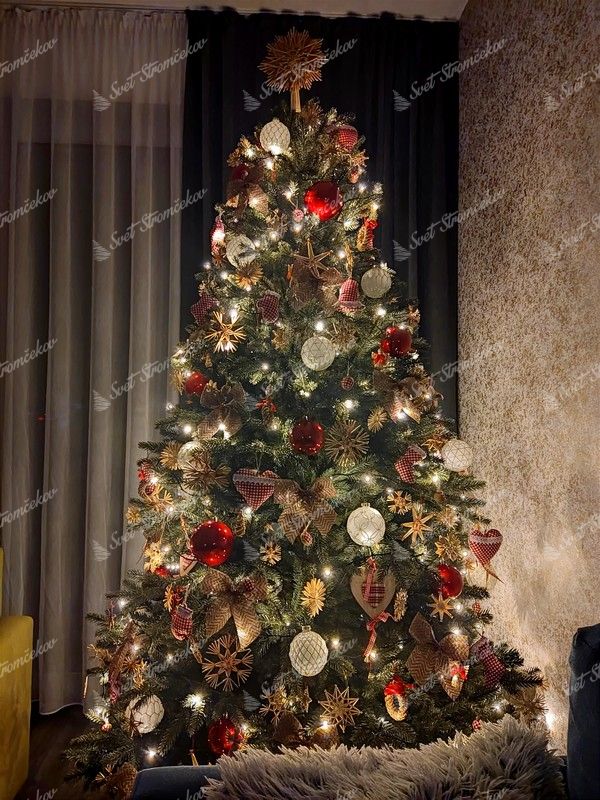 Zelený umelý vianočný stromček, ozdobený slamenými ozdobami v provensálskom štýle, s teplým bielym osvetlením.