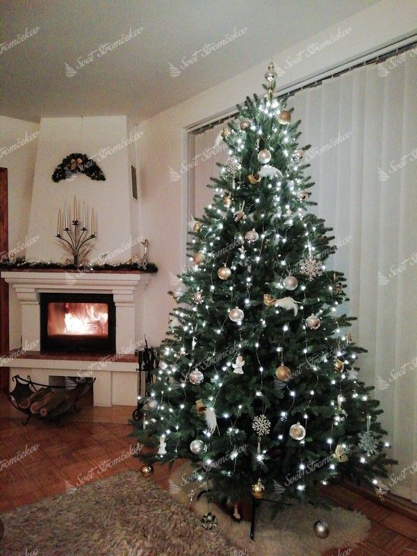 FULL 3D umelý vianočný stromček s bielo zlatými ozdobami s jemným bielym osvetlením pri krbe.