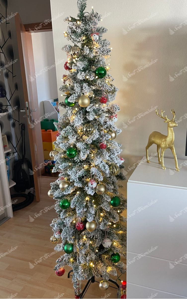 Umelý vianočný stromček Smrek Biely Štíhly 180cm LED310 je ozdobený červenými, zelenými a zlatými ozdobami.