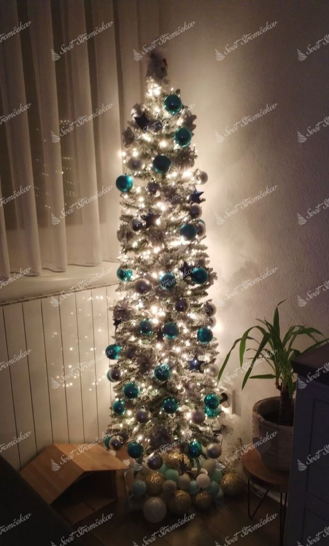 Umelý vianočný stromček Smrek Biely Štíhly 180cm je ozdobený tyrkysovými a striebornými ozdobami.