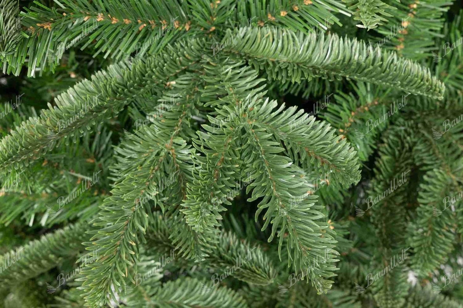Detailaufnahme des künstlichen Weihnachtsbaums 3D Colorado-Tanne auf Stamm, Der Zweig ist mit 3D-Nadelwerk in abgerundeter Form und natürlichem Grün ausgestattet. Das Nadelwerk wirkt täuschend echt